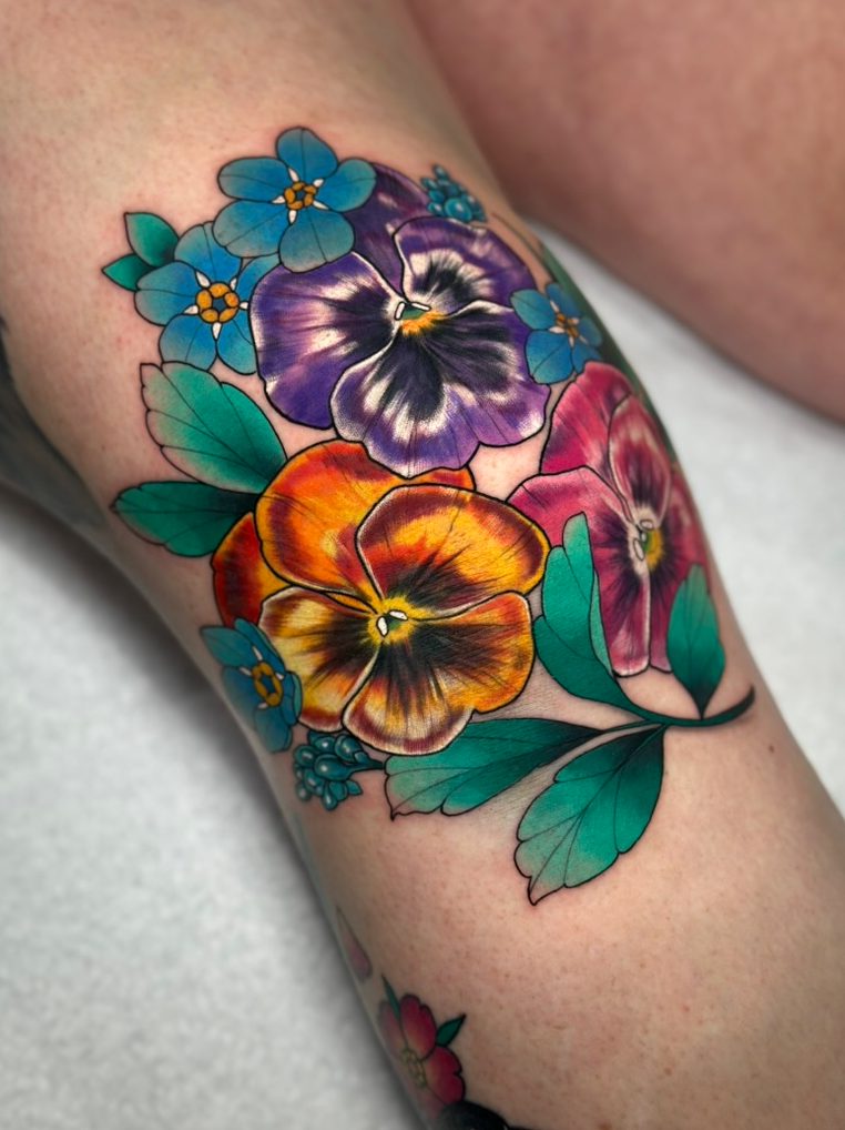 Pansies and forget-me-nots tattoo on the knee by Tia Berry, colour tattoo artist in Vancouver